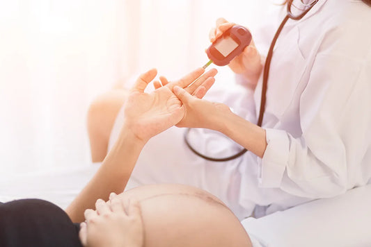 Eine schwangere Frau bekommt ihren Blutzucker gemessen - während medizinisches Personal ein Messgerät verwendet